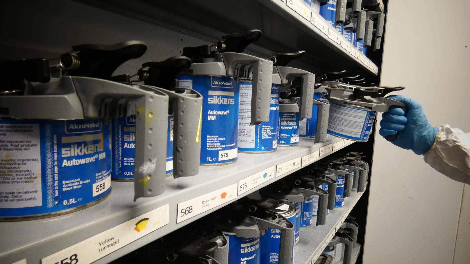 Shelving with paint pourers and a hand pulling one of a shelf